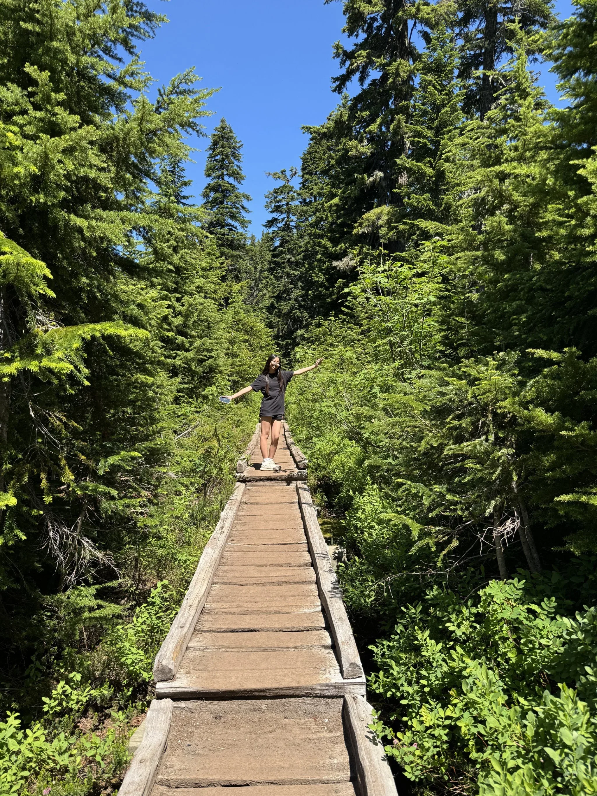 My granddaughter with arms extended on a wooden path.